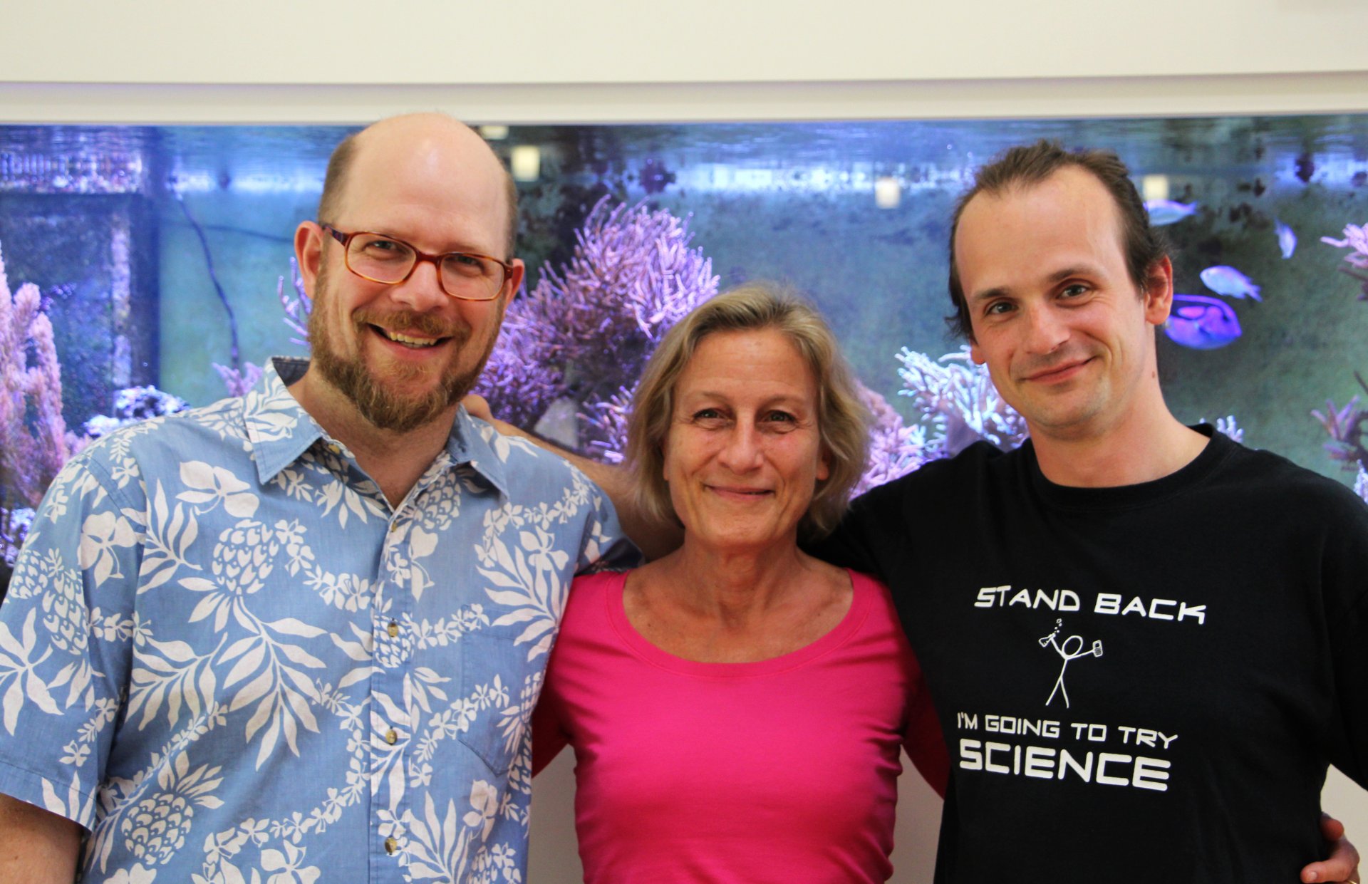 Harald Gruber-Vodicka, Nicole Dubilier und Niko Leisch vor dem Aquarium im Foyer des Max-Planck-Instituts für Marine Mikrobiologie. Auch in diesem Korallenaquarium lebt Trichoplax mit seinen Symbionten. (© Christian Borowski / Max-Planck-Institut für Marine Mikrobiologie)