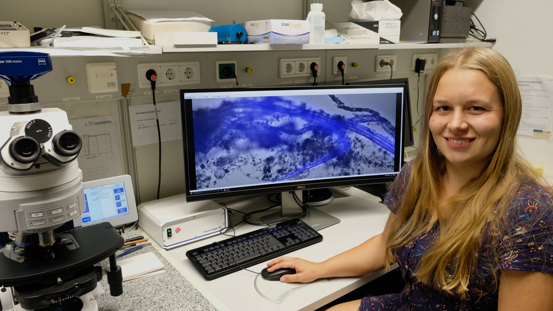 Clarissa Karthäuser im Labor. Auf dem Bildschirm ist ein angefärbtes und stark vergrößertes Partikelteilchen zu sehen. (©Max-Planck-Institut für Marine Mikrobiologie/ C. Karthäuser)